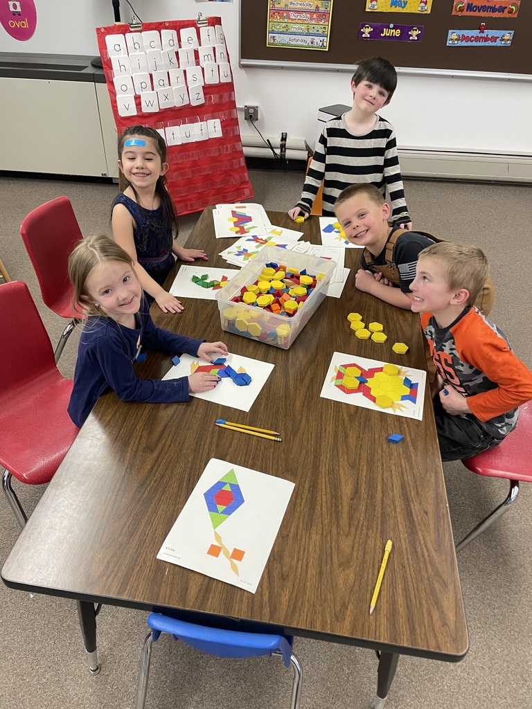 Kindergarteners making pictures out of shapes.